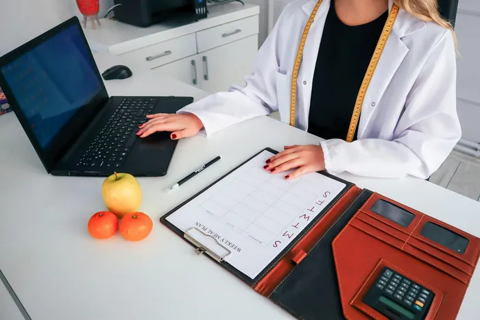 Diyetisyen masasında açık bir defter ve dizüstü bilgisayar
